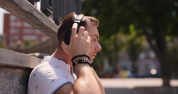 Man Puts on Big Headphones in a Park