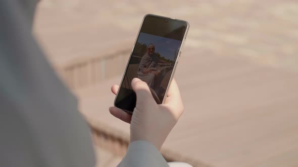 Muslim Woman Looking Through Photos on Smartphone