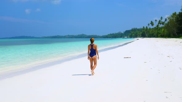 Woman sunbathing walking on white sand beach turquoise water tropical coastline