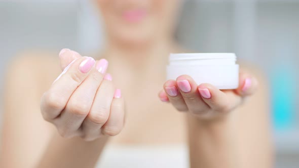 Closeup of Female Hands Holding Jag with White Skin Care Cosmetics Cream