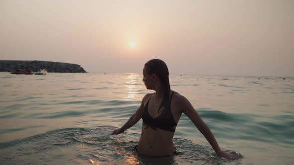 Girl Bathes in the Sea Against the Backdrop of the Sunset