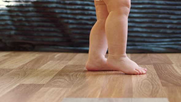 Babys Small Legs Take Their First Steps on the Floor Closeup Legs Side View