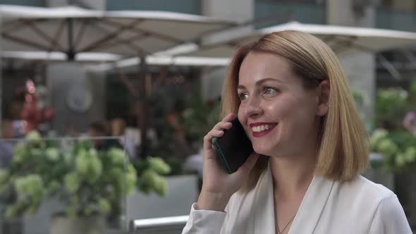 Business woman talking on the phone with employees outdoors near the business center.