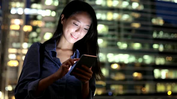 Woman use of mobile phone in the city at night 