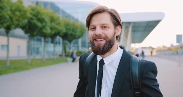 Man with Well-Maintained Beard in Stylish Clothes with Backpack Posing on Camera