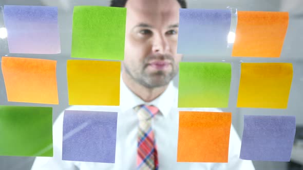 Man Working On Sticky Notes Attached on Glass in Office