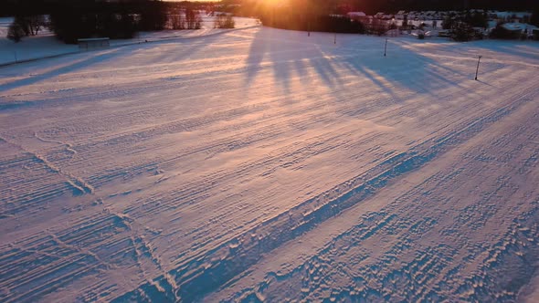 Drone shot of mountains, fields, and landscape in winter at golden hour, sunrise with snow, flying o