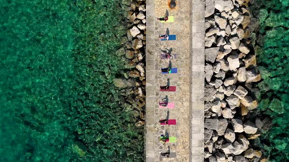 Aerial view of group practicing yoga at artificial pier, Veli Losinj, Croatia.