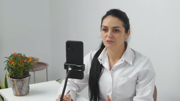 Young Female Nutritionist Talking on Video Chat Using Mobile at Work