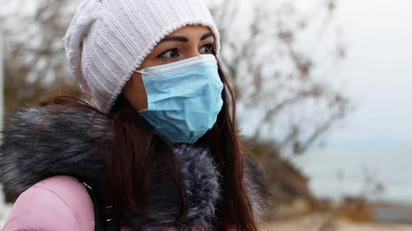 A woman with long dark hair in a mask from air pollution and the Covid19 coronavirus walk