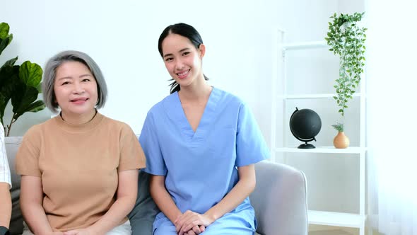 Portrait of Asian senior family and a young caregiver sitting on a chair in a living room