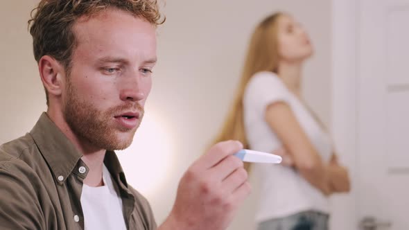 Frustrated Young Man Look at Pregnancy Test at Home