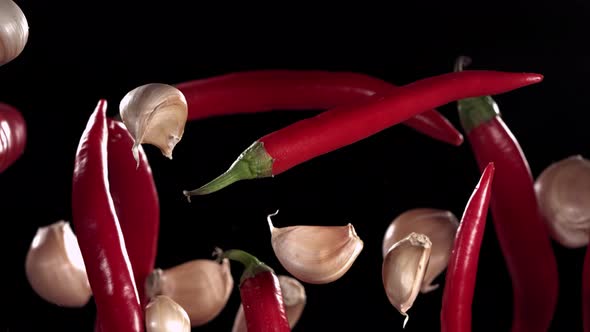 Super Slow Motion Shot of Flying Red Chilli Peppers and Garlic
