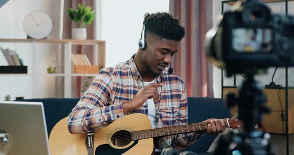 Guy in Wireless Headset Recording His Guitar Play on Videocamera for Internet audience