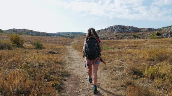 Girl with Backpack and Poles Going Through Mountain Plato