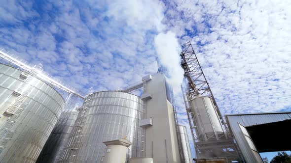 Modern factory for grain storage. Massive smoke from industrial plant