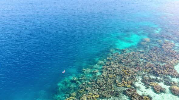 Aerial slow motion: woman snorkeling on coral reef tropical caribbean sea, turquoise blue water