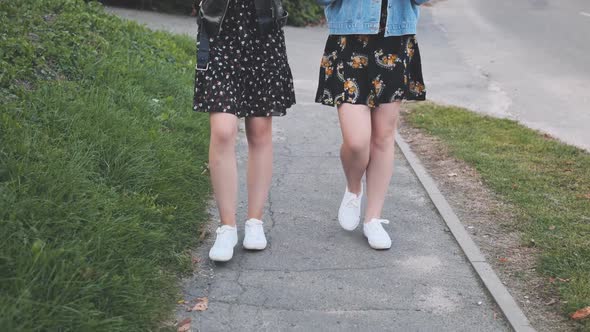 Two Girlfriends in White Sneakers Walk Down the Street