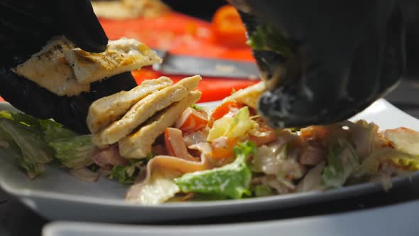 Male Arms Putting Pieces of Fried Chicken Unto Fresh Ingredients in White Plate at Cuisine