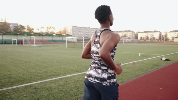 A Young Black Girl Training at the City Stadium and Runs on the Treadmill Around the Football Field