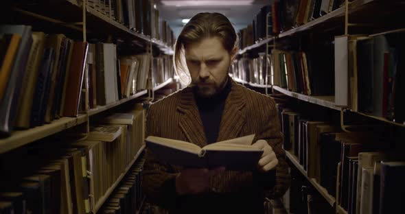 Bearded Man Reading Book in Dark Library