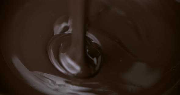 Pouring melted dark bitter chocolate flow.Pastry close up shot.