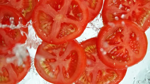 Super Slow Motion Shot of Tomato Slices Falling Into Water on White Background at 1000Fps.