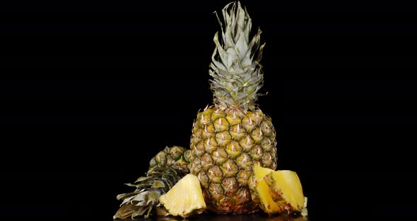 Sliced and Whole Pineapple with Greens Slowly Rotates. 