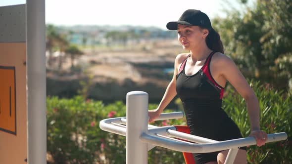 Medium Shot of Young Motivated Sportswoman Exercising on Sport Equipment Outdoors