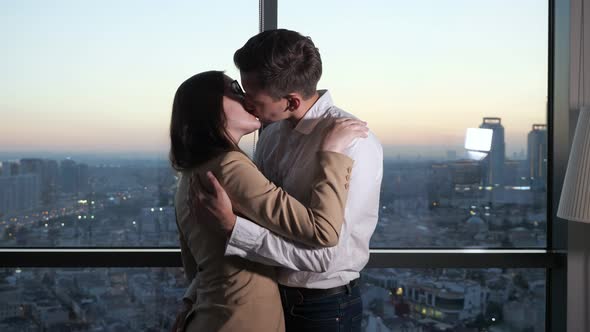 Couple Man and Woman are Dancing and Kissing Near the Panoramic Window with City View