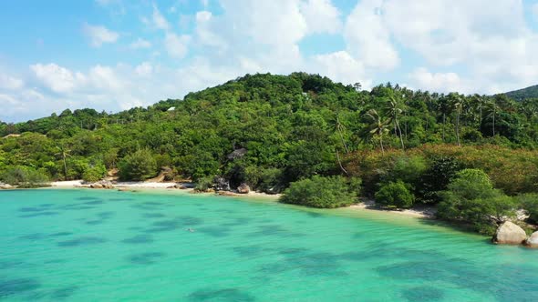 Aerial flying over scenery of tropical tourist beach vacation by blue lagoon with white sand backgro