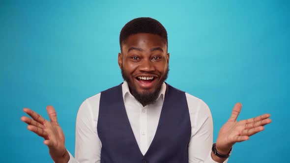 Surprised Young African Man Showing Thumbs Up Against Blue Background in Studio