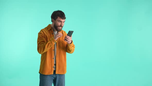 Happy Man with Cellphone Rejoicing at Winning Bets