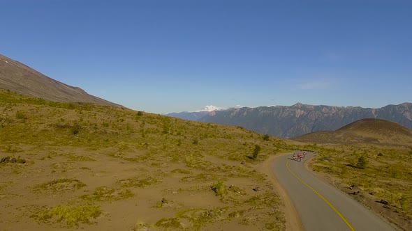 Aerial view of cyclists and a vehicle traveling along a winding road near Osorno, Los Lagos Region,