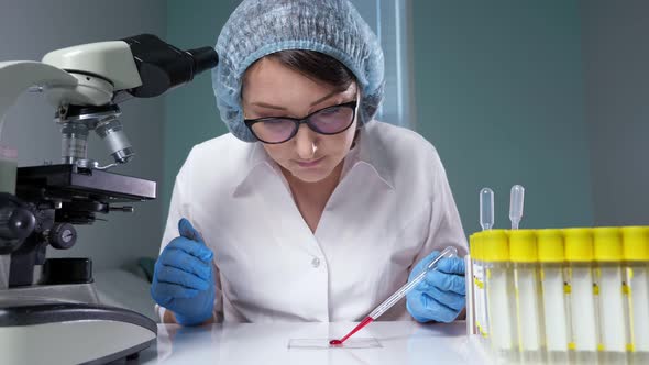 Lab Assistant Drips Blood and Looks Through Magnifier Glass