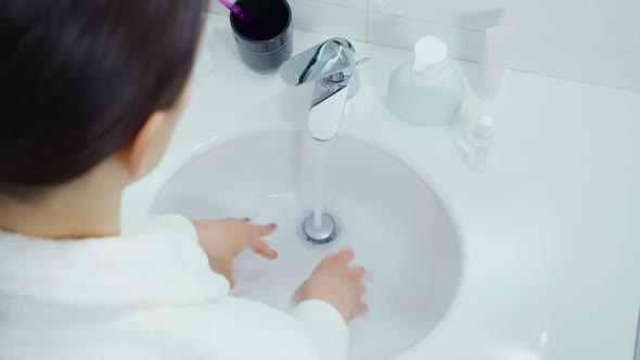 Young Woman in Bathrobe Washing Hands with Soap