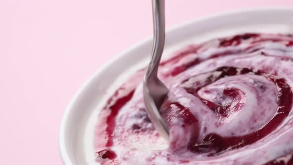 Yogurt with berry jam in spoon, blueberry whipped cream