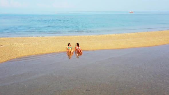 Female models happy together on relaxing shore beach trip by shallow sea and clean sandy background 