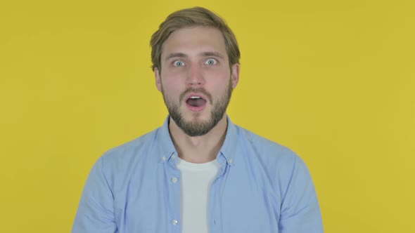 Surprised Young Man Feeling Amazed on Yellow Background