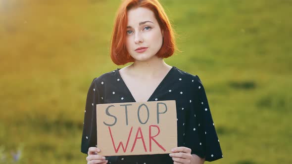 Unhappy Caucasian Young Redhead Woman Activist Hold Demonstrating Banner with Inscription Stop War