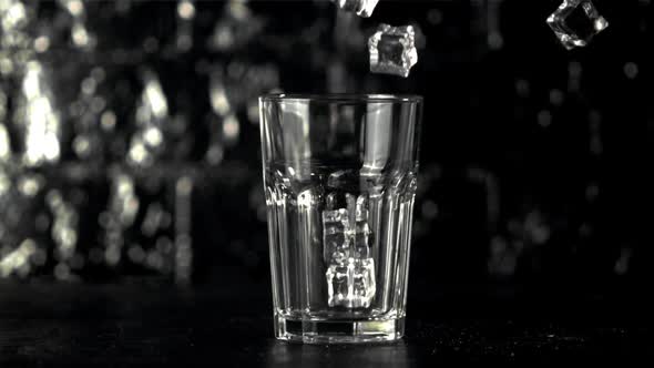 Super Slow Motion Ice Cubes Fall Into a Glass on the Table