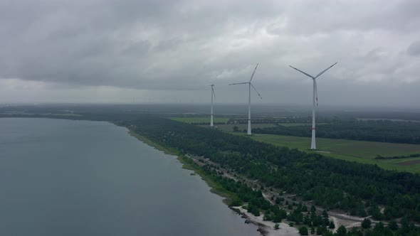 Three windmills generating renewable energy, standing next to a lake in a rural landscape, concept f