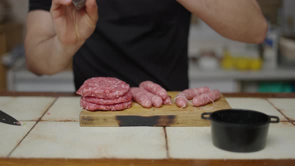 Unrecognizable Man Preparing Sausages and Burgers in Cutting Board