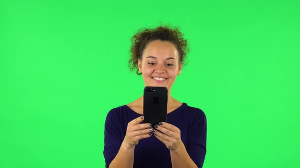 Portrait of Curly Woman Talking for Video Chat Using Mobile Phone and Rejoice . Green Screen