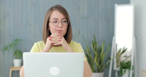 Young Beautiful Woman is Sittting in Front of a Laptop and Thinking