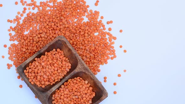 red lentils  in wooden plate on a white background. It turns around itself