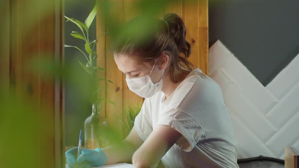 Young Student Teenager Girl in Protective Mask Standing Near Window on Home Self Isolation