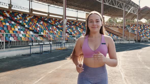 Beautiful Young Woman Jogging at Sports Stadium