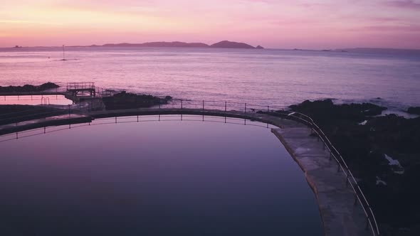 Guernsey tidal bathing pools with Herm Island behind at sunrise, Channel Islands, UK. Aerial drone v