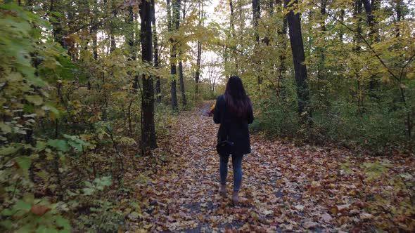 Girl with Flowers Walks in the Autumn Forest